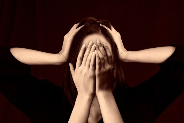 Person covering face expressing distress related to bipolar disorder thoughts and misconceptions.