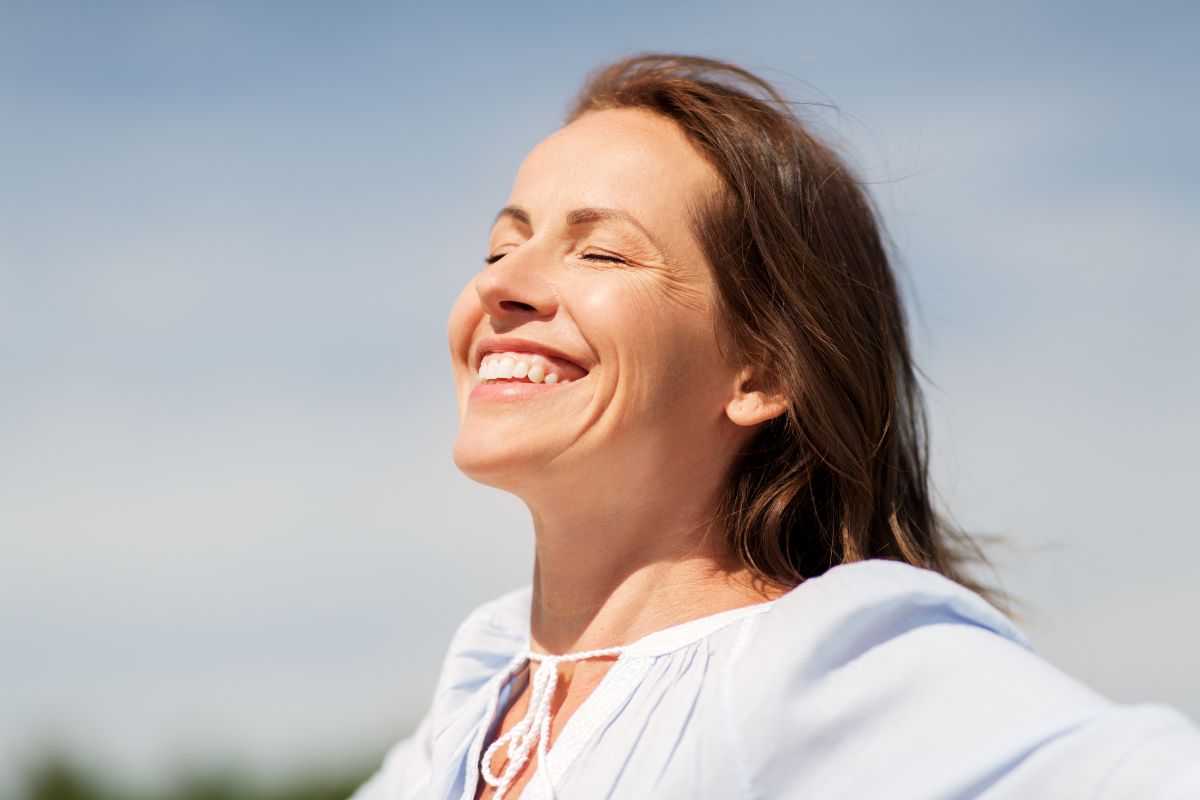 Woman smiling with eyes closed representing emotional well-being and mental health.