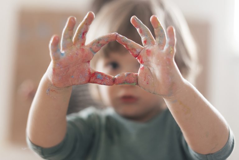 Autistic child's hands forming a heart shape with paint, illustrating frustration and helpful tips.